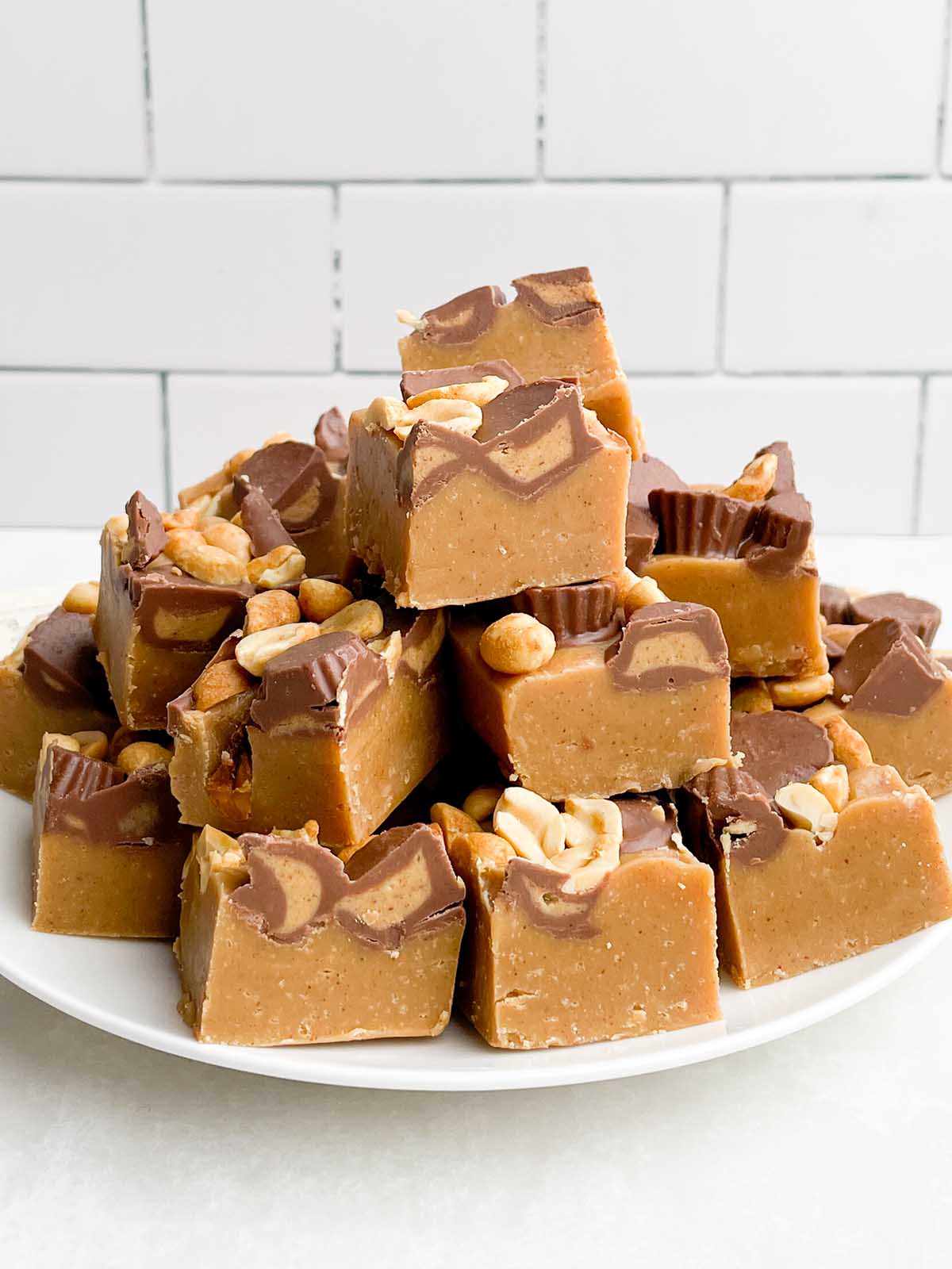 Squares of no bake peanut butter fudge on a white plate. 