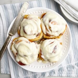 four cinnamon rolls with frosting on a white plate