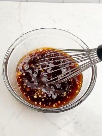teriyaki marinade and a clear whisk in a clear bowl.