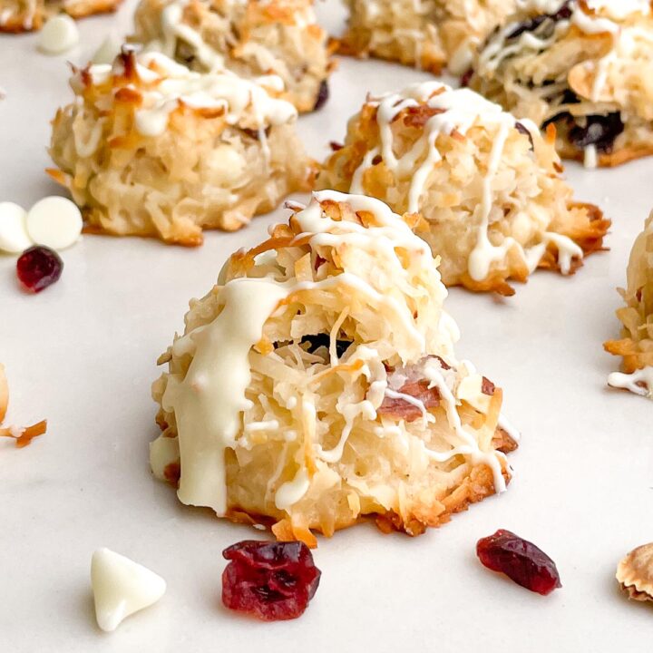 cranberry almond macaroons with white chocolate drizzle on a white countertop