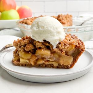 side view of apple pie with graham cracker crust topped with vanilla ice cream