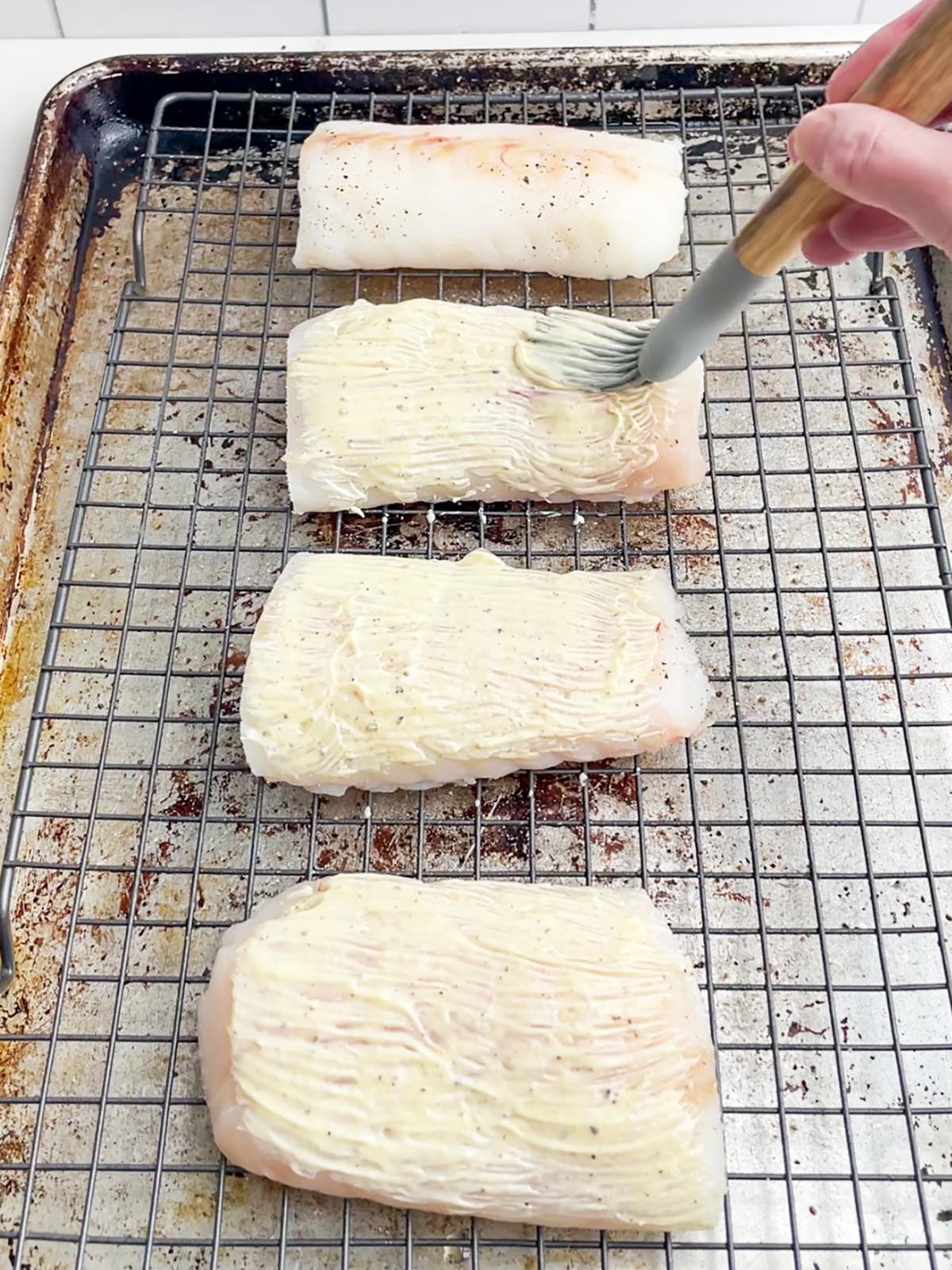 brush spreading mayonnaise mixture on top of cod fillets