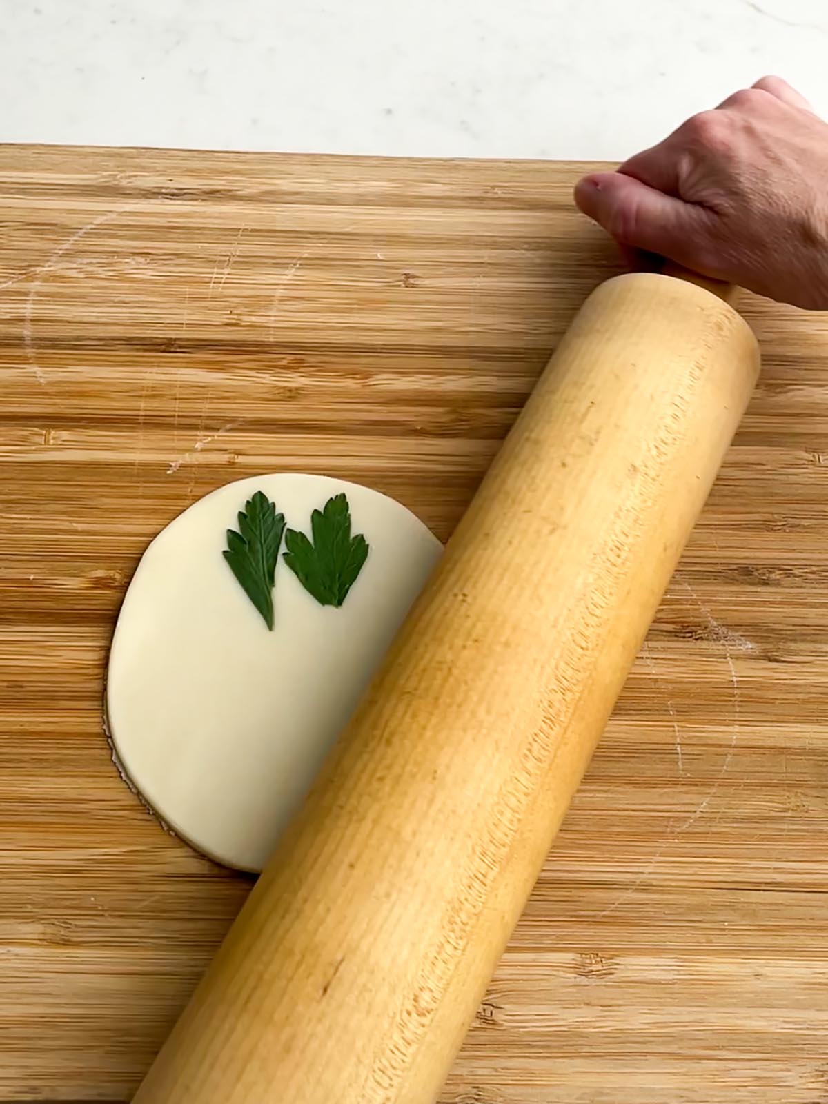 rolling pin over a pie dough round with herbs