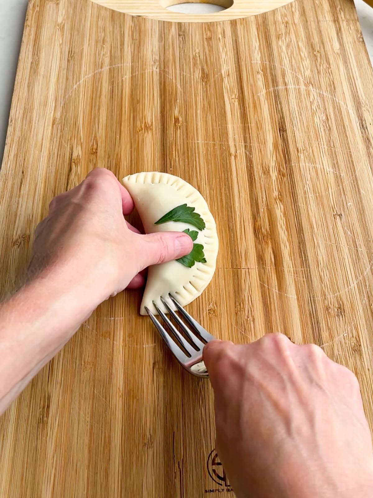 fork crimping the edges of an unbaked empanada