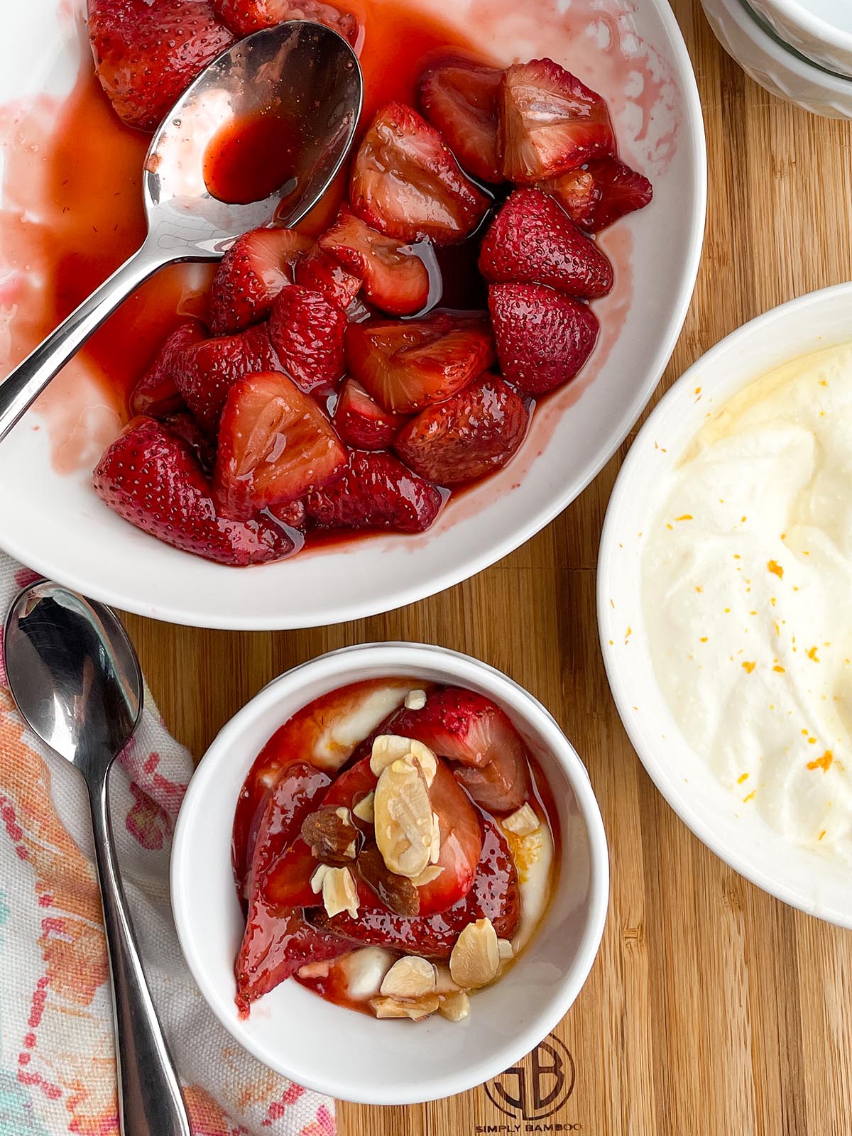 bowls of balsamic roasted strawberries  and whipped ricotta with toasted almonds on a wooden board