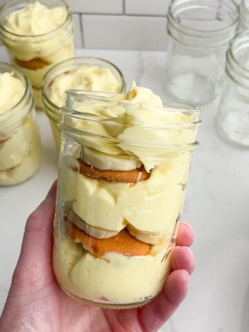 hand holding a mason jar with banana pudding.
