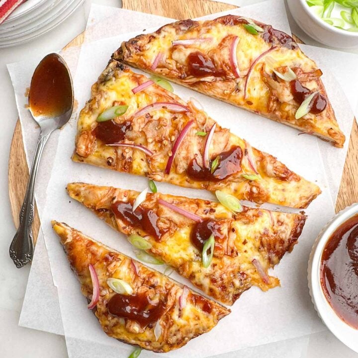 bbq chicken flatbread cut into slices on parchment covered wooden cutting board