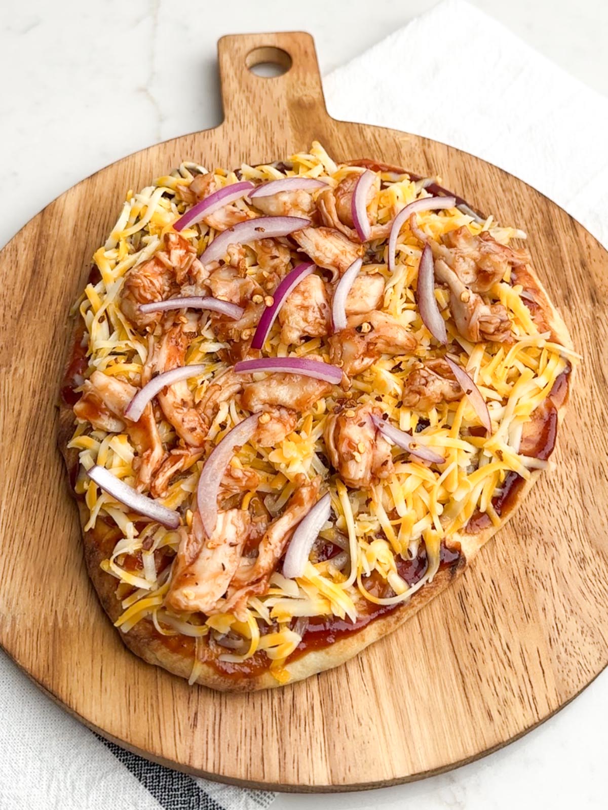 unbaked bbq chicken flatbread on a wooden cutting board