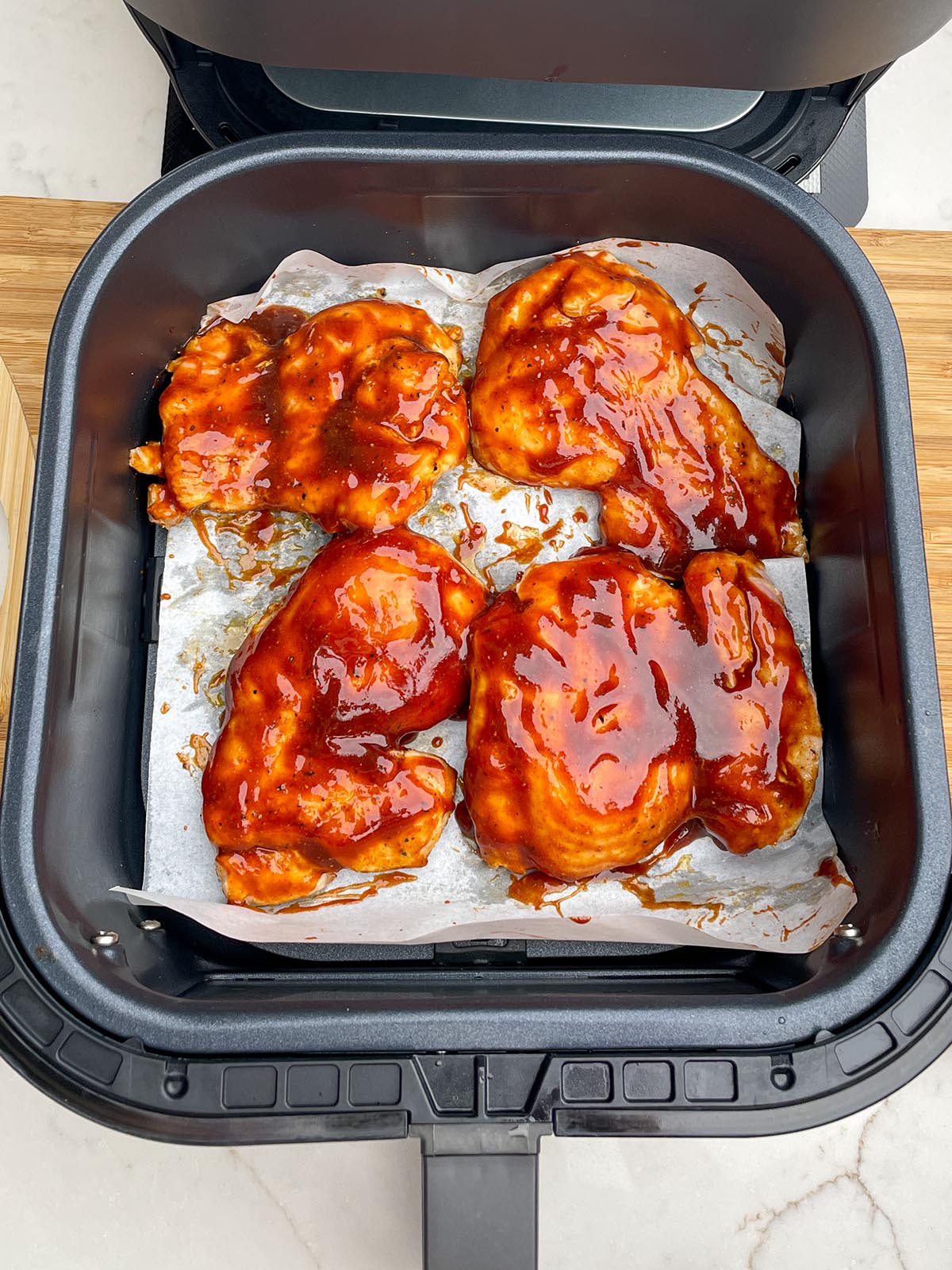 boneless skinless chicken thighs covered in bbq sauce in air fryer