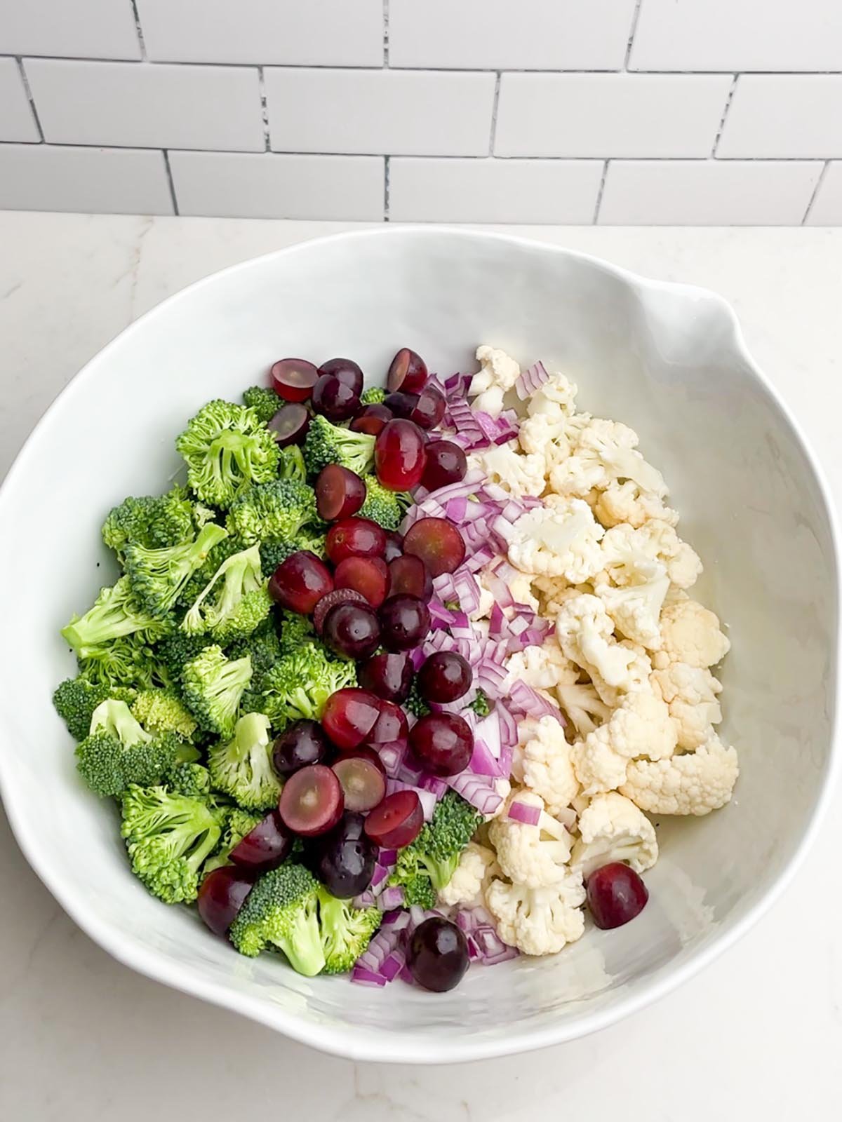 Broccoli cauliflower bacon salad ingredients in a white bowl