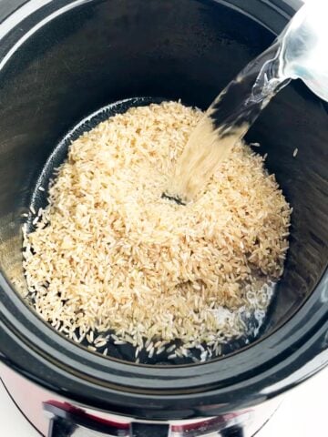 water and brown rice in a black crock pot.