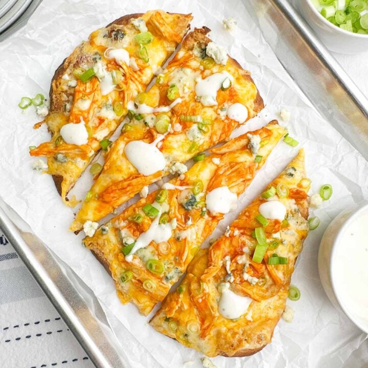 slices of buffalo chicken flatbread on a baking sheet lined with parchment paper