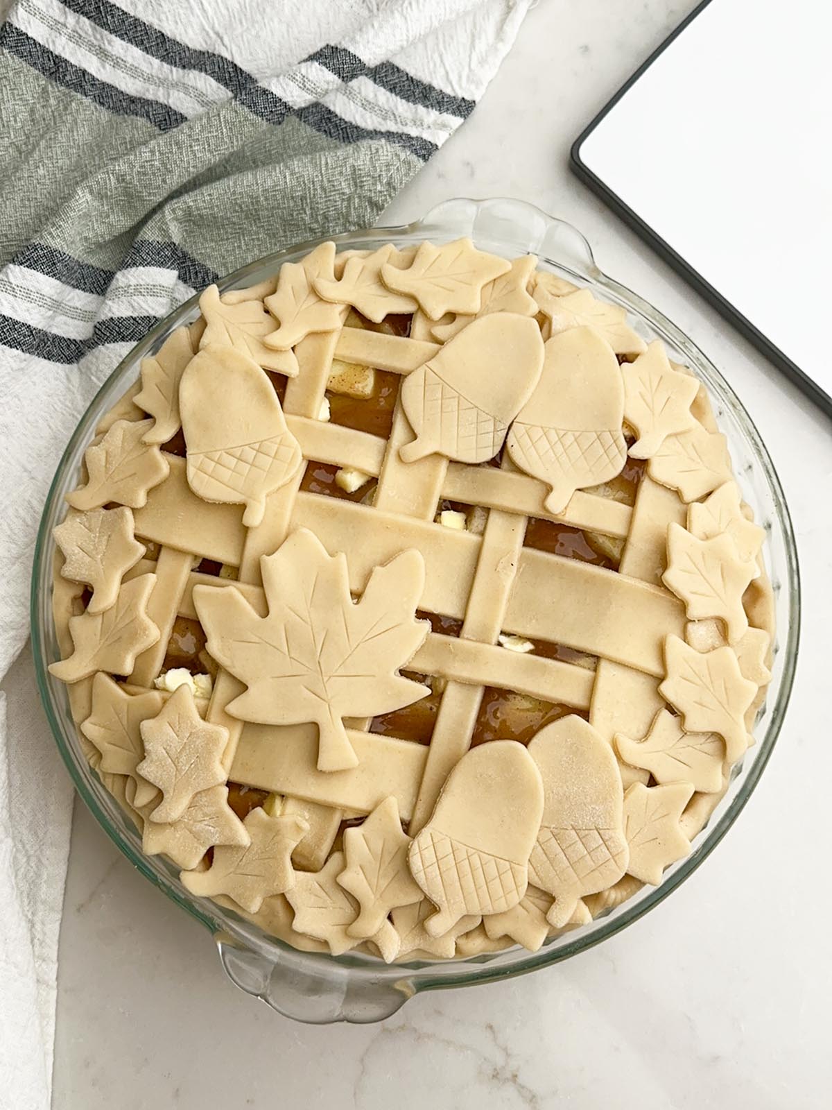 Plaid lattice topped apple pie with pie dough cutouts.