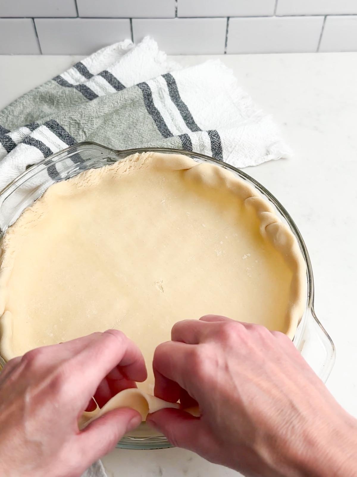 hands pressing pie dough into pie plate.