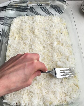 hand holding a fork pressing the coconut into the cream cheese mixture. 