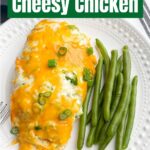 cheesy baked chicken on white plate with green beans