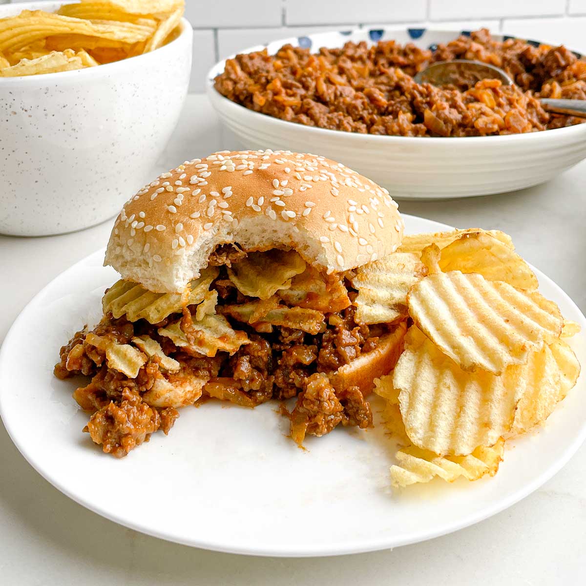 chicken gumbo sloppy joe on a white plate with potato chips.