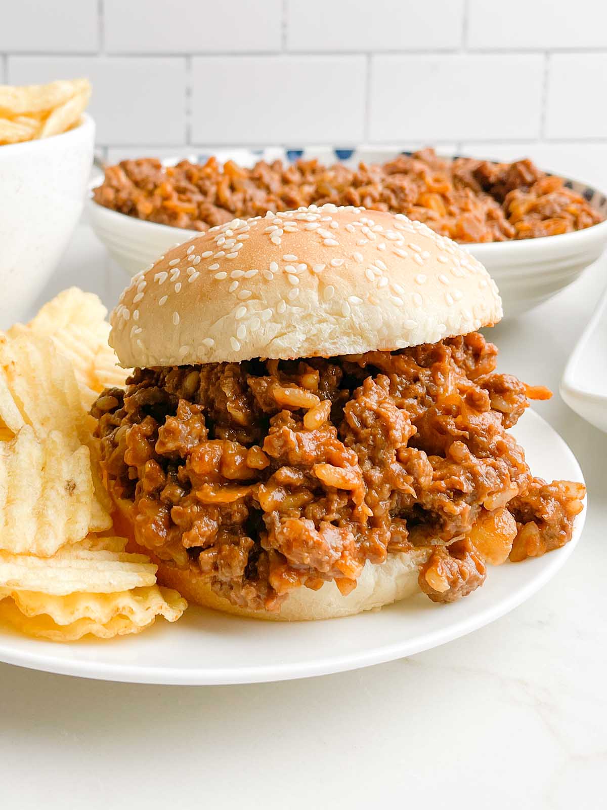 chicken gumbo sloppy joe on a white plate with potato chips.