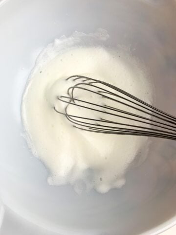 beaten egg whites in a white bowl. 