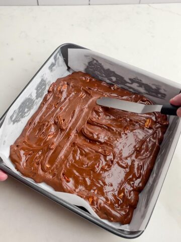 offset spatula spreading chocolate pecan mixture into pan.