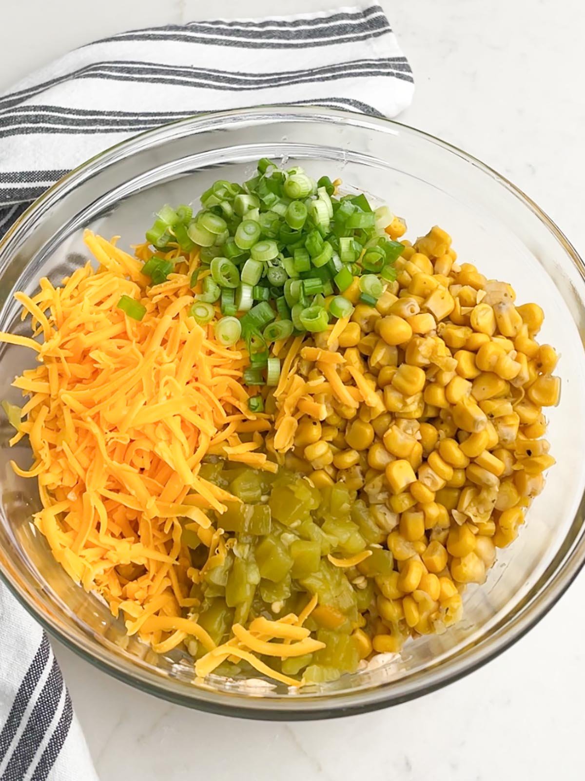 cheese, green onions, green chiles, and corn in a clear bowl