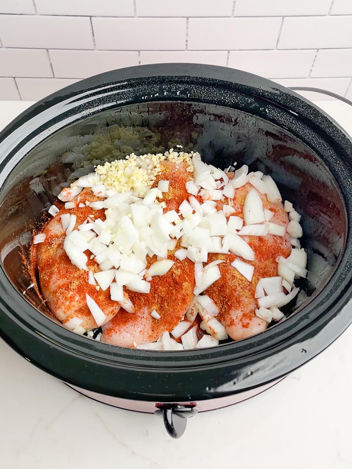 chicken, spices, onion, and garlic in black slow cooker