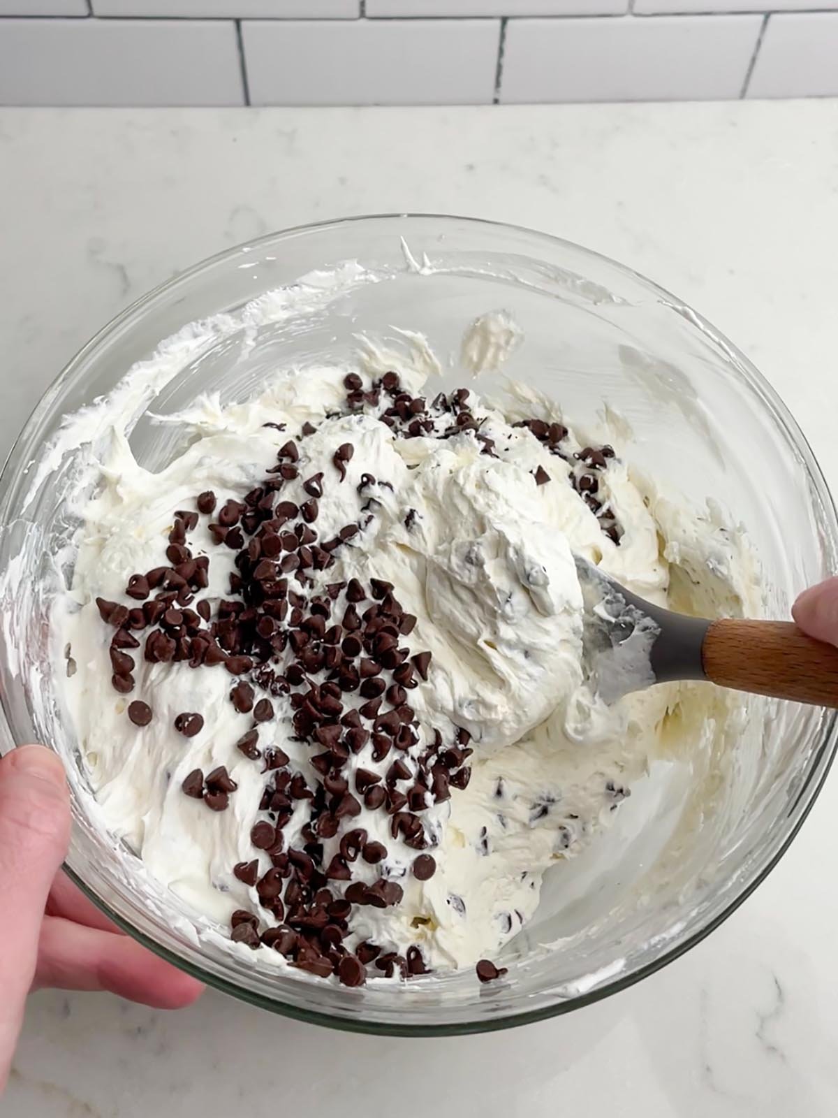 spatula folding the Cool Whip and chocolate chips into the cream cheese chocolate chip dip