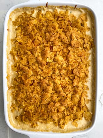 Cream Cheese Corn Casserole with browned Fritos in a white casserole dish. 