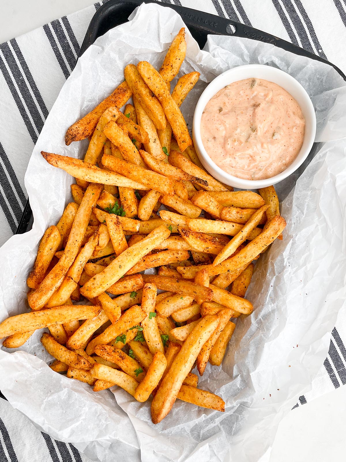 cooked frozen seasoned fries in pan with parchment paper and dipping sauce