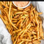 cooked frozen seasoned fries in pan with parchment paper and dipping sauce