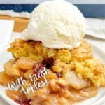 cake mix apple cobbler on a white plate with a scoop of vanilla ice cream on top