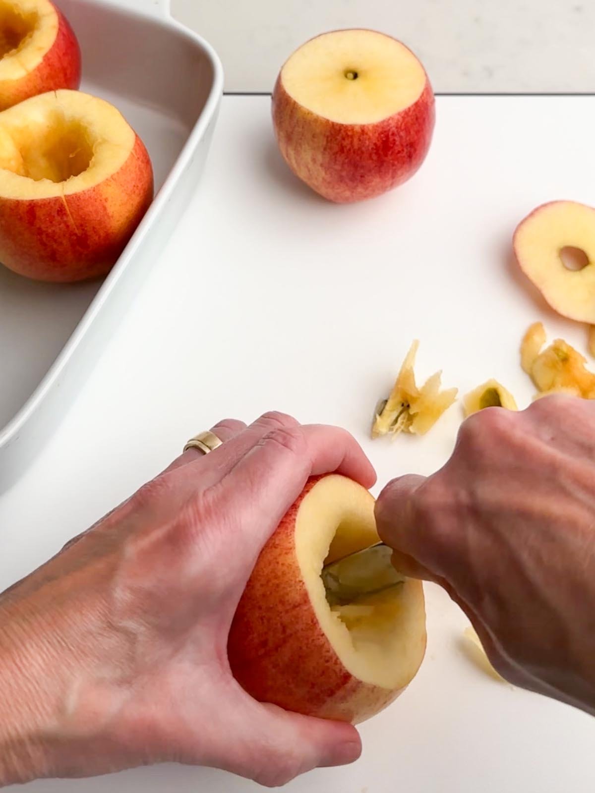 hands holding an apple and a spoon coring an apple