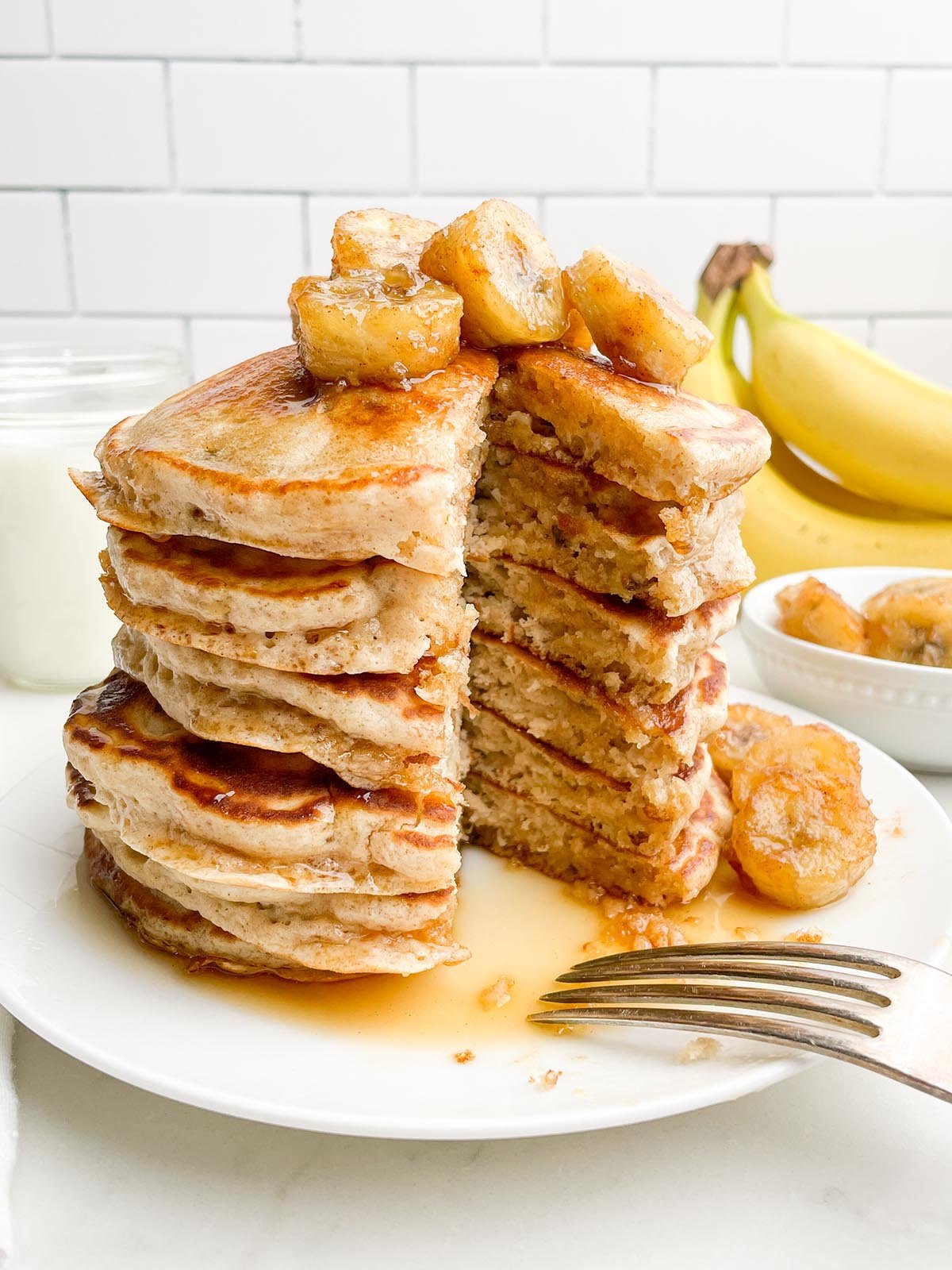 stack of banana pancakes from pancake mix topped with bananas and maple syrup.
