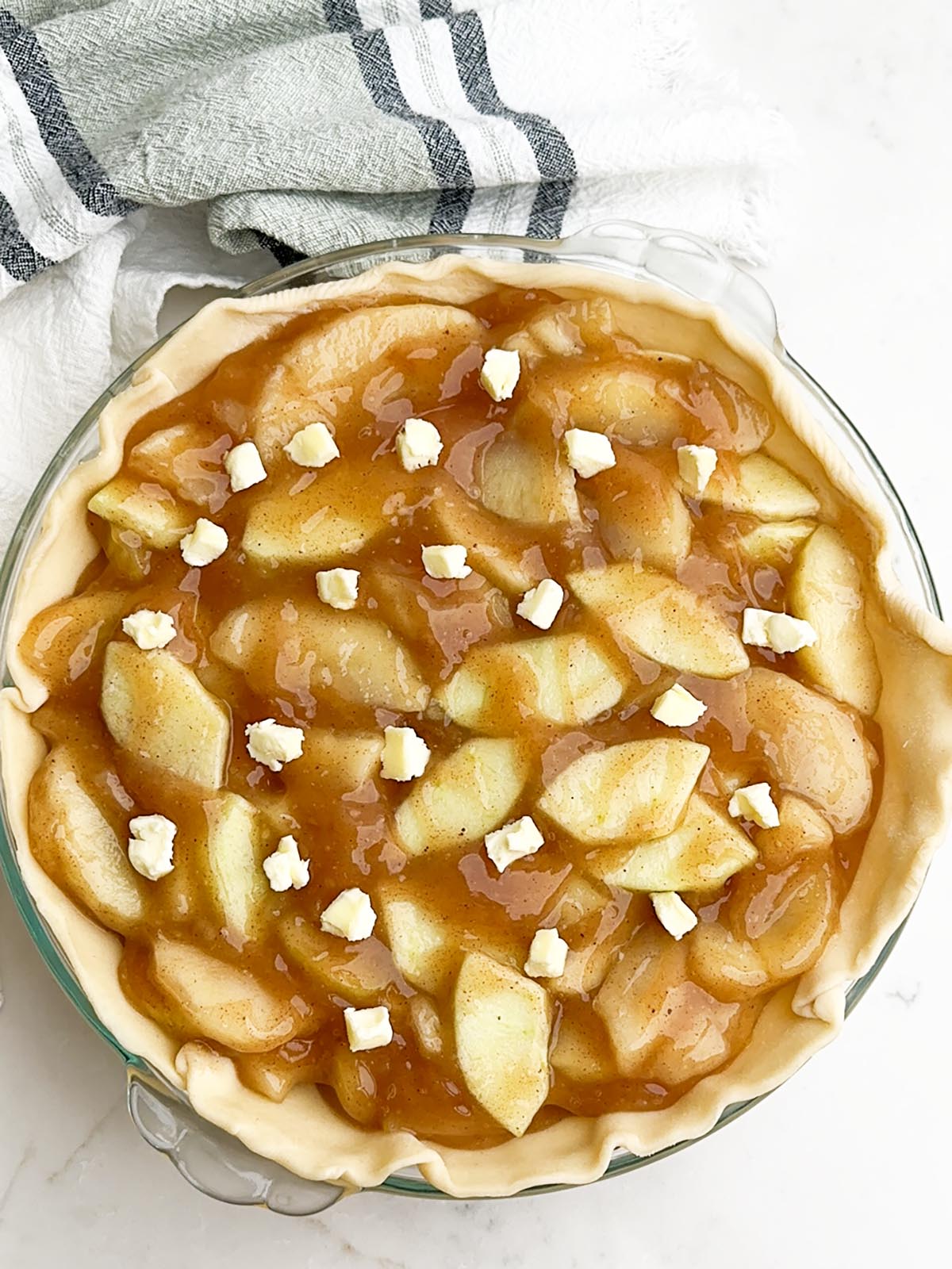 Apple pie filling in a pie plate topped with small dots of butter.