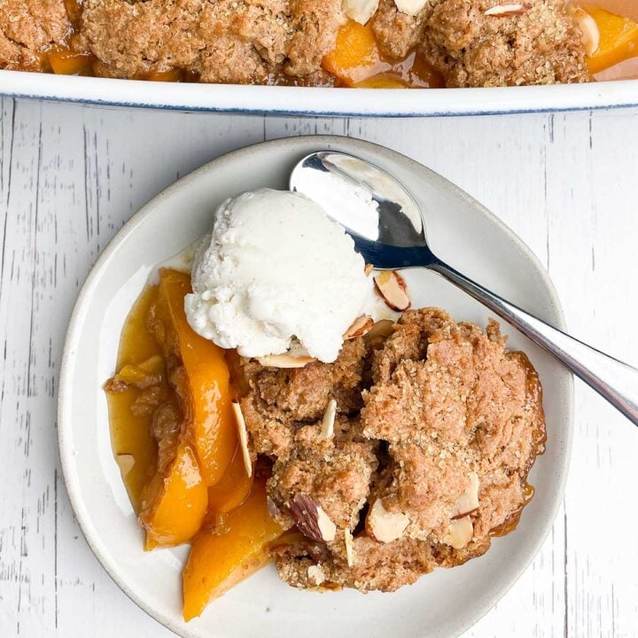 white plate with peach cobbler and ice cream