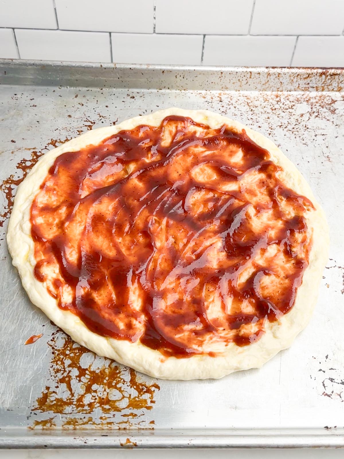 bbq sauce spread over pizza dough