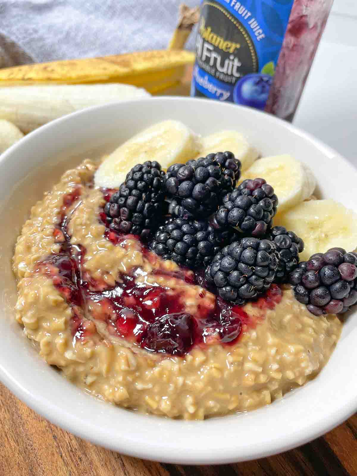 Peanut Butter & Jelly Banana Overnight Oats with banana, blackberries, and jelly in a white bowl