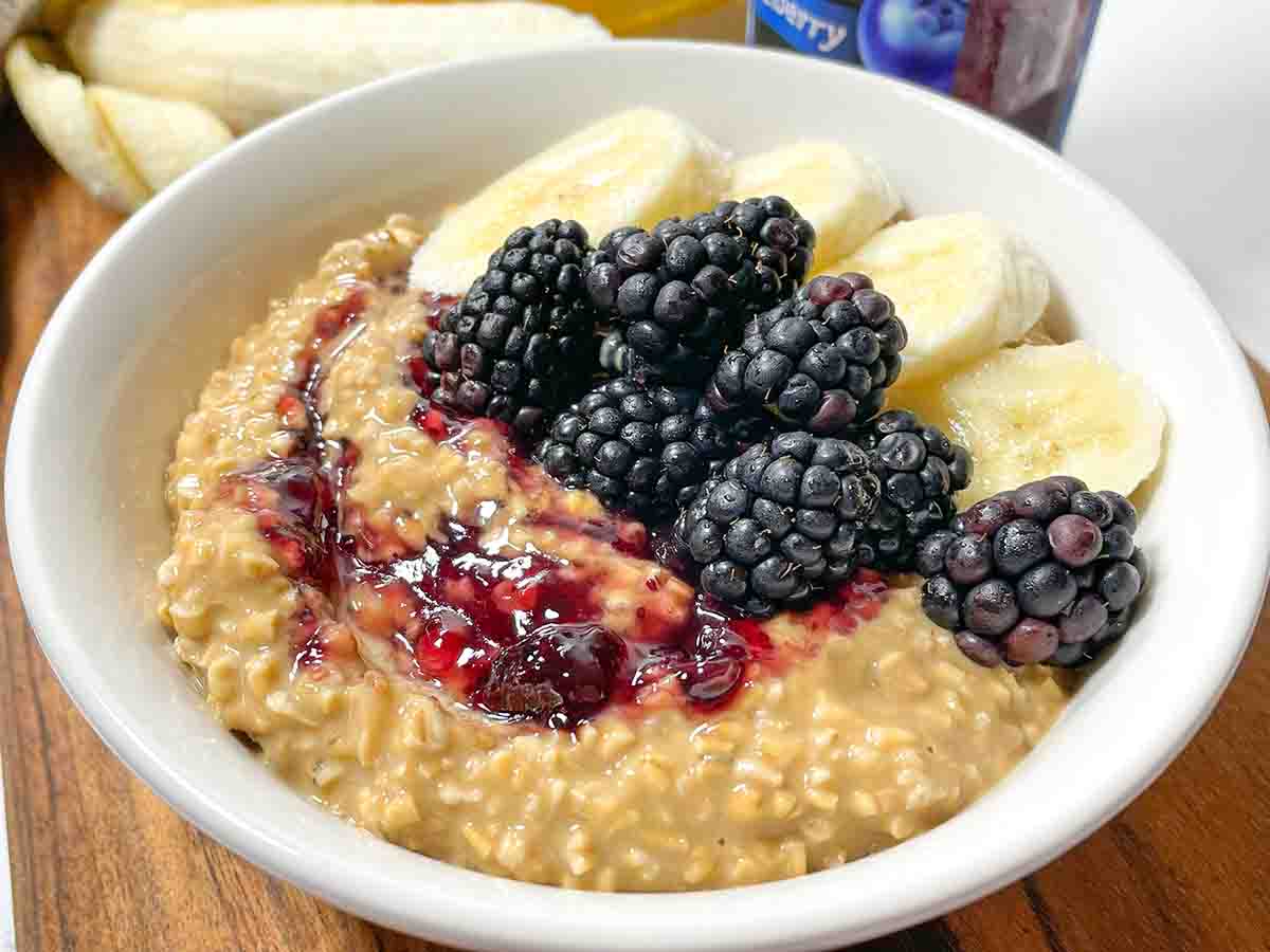 Peanut Butter & Jelly Banana Overnight Oats with banana, blackberries, and jelly in a white bowl
