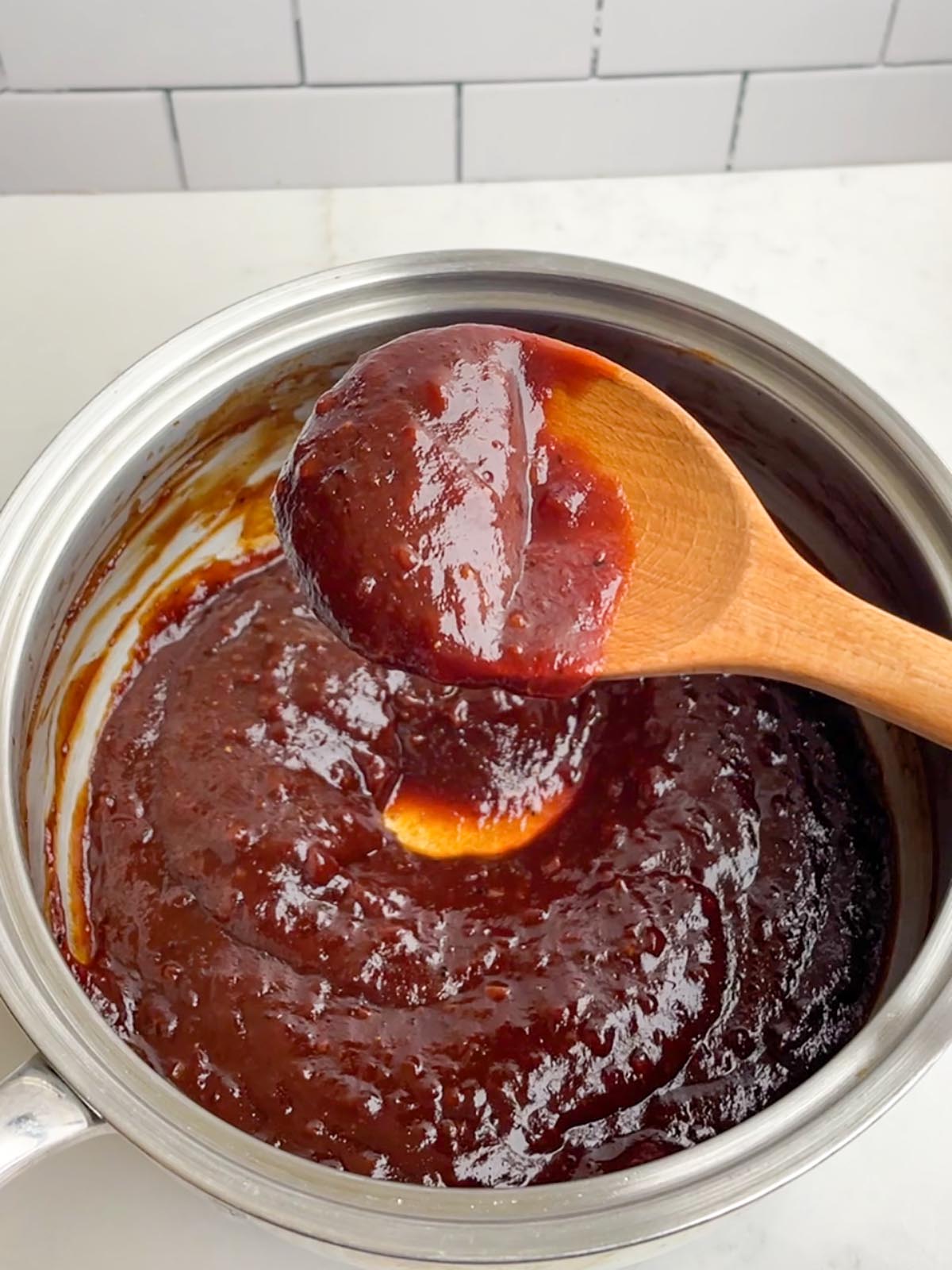 sauce pan with jack daniels bbq sauce and a wooden spoon