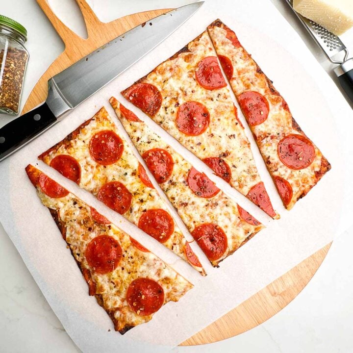pepperoni lavash pizza cut into triangles on parchment on a wooden cutting board