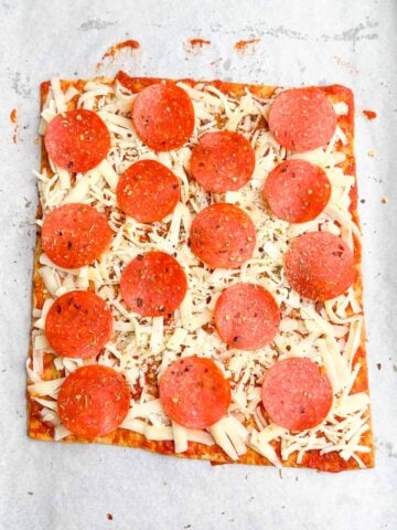 unbaked pepperoni lavash pizza on parchment paper.