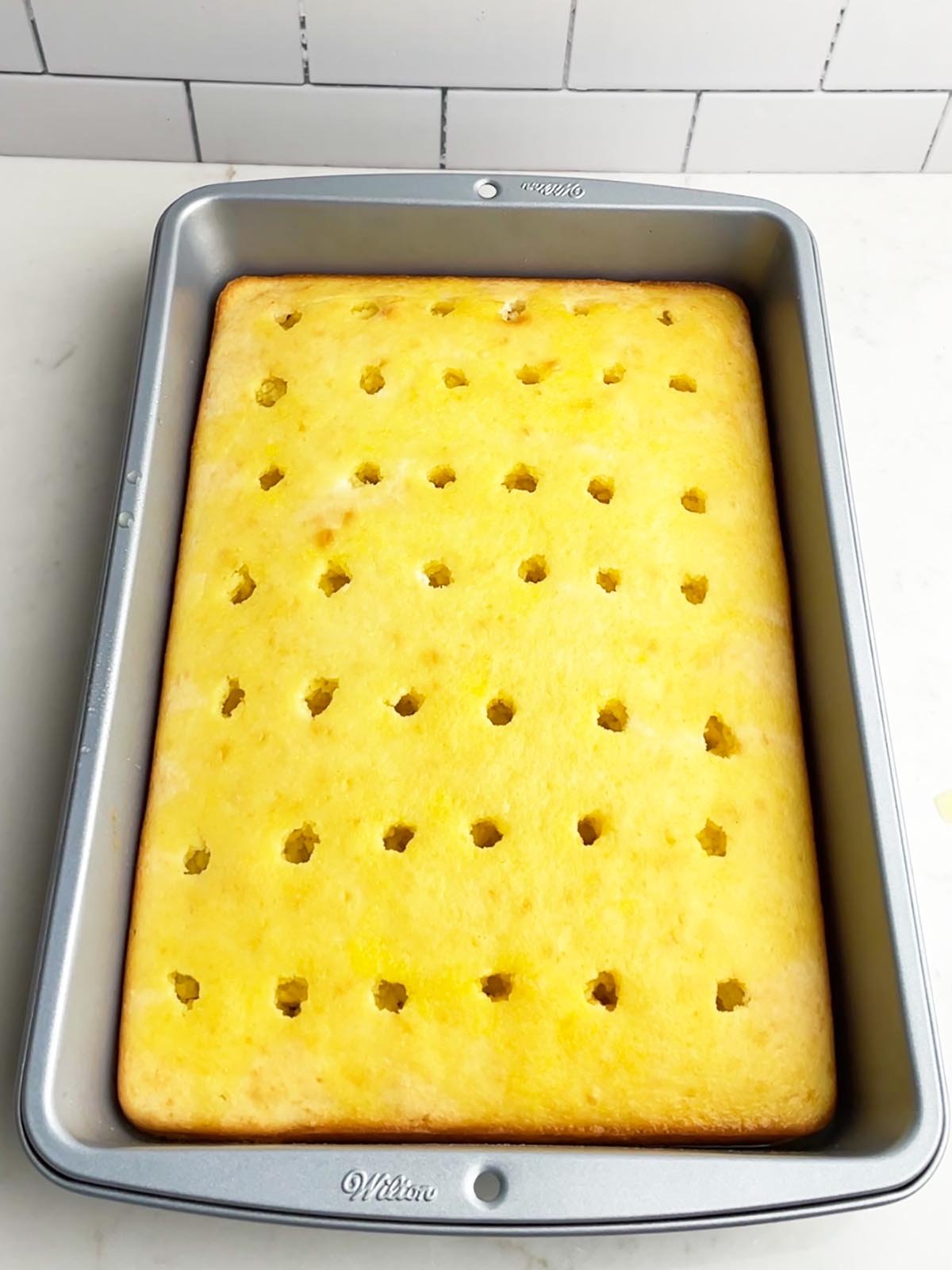 white cake with holes poked on top and lemon jello poured over the top