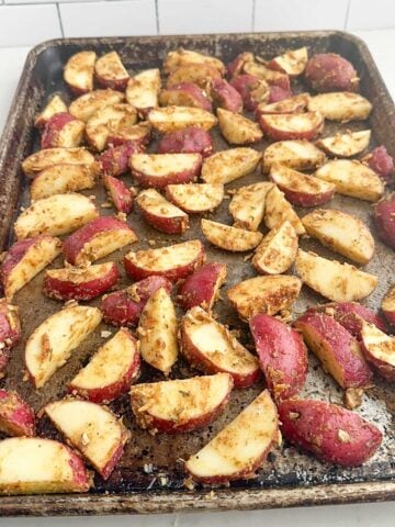 raw potatoes tossed with lipton onion soup mixture on a baking sheet.