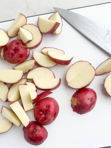 red potatoes cut into 1" thick pieces on a cutting board. 