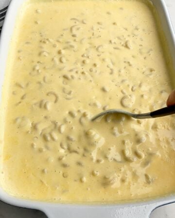 macaroni and cheese in a baking pan with a spoon in it. 