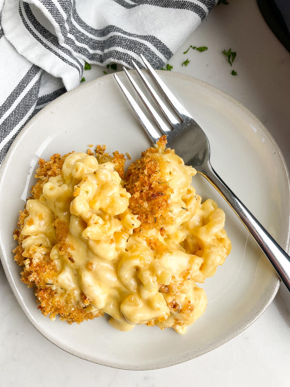 plate with macaroni and cheese on it and a fork next to it.