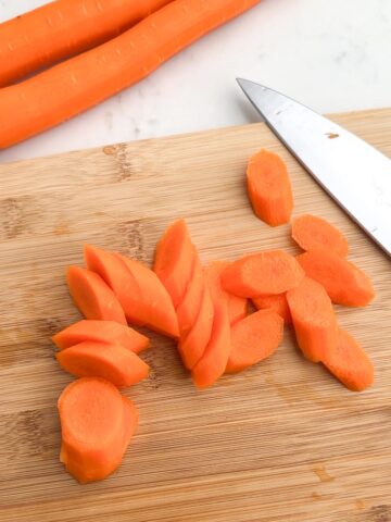 sliced carrots on a wooden cutting board.