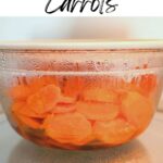 steamed carrots in a clear bowl covered with a plate in a microwave.