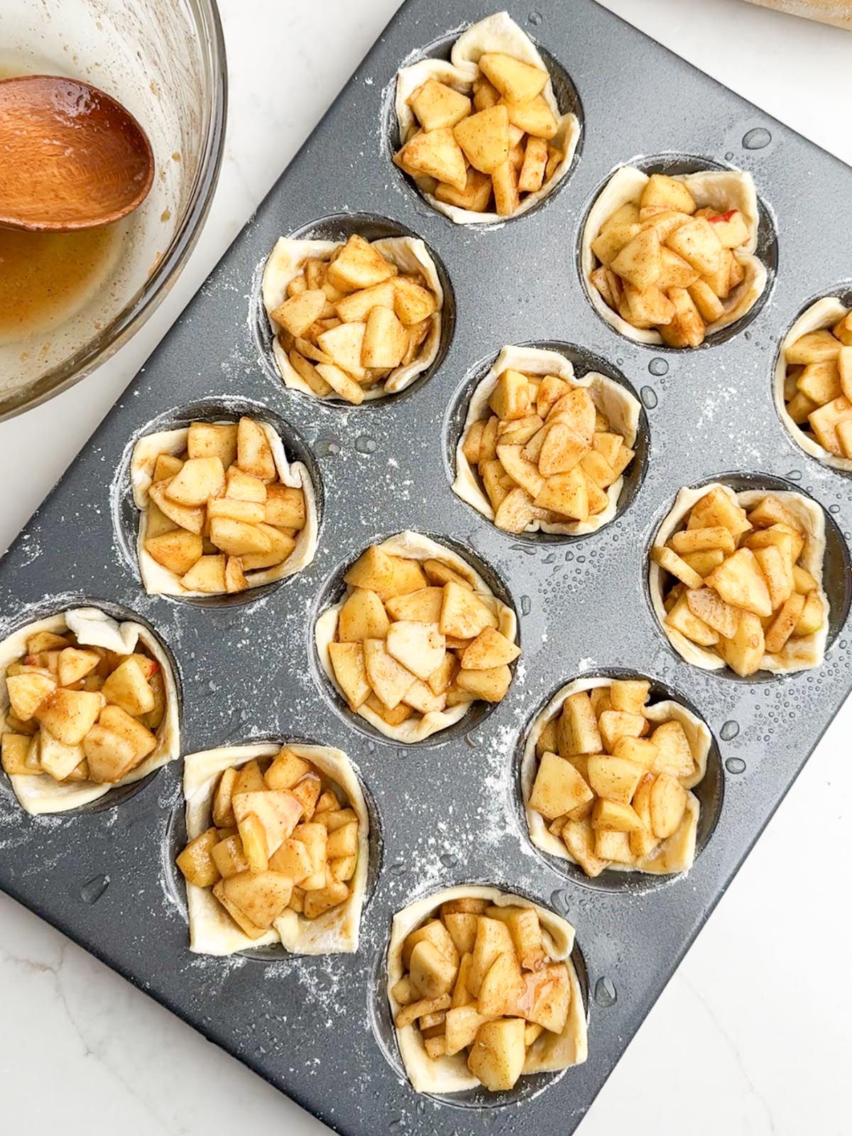 muffin tin with puff pastry cups filled with apple pie filling