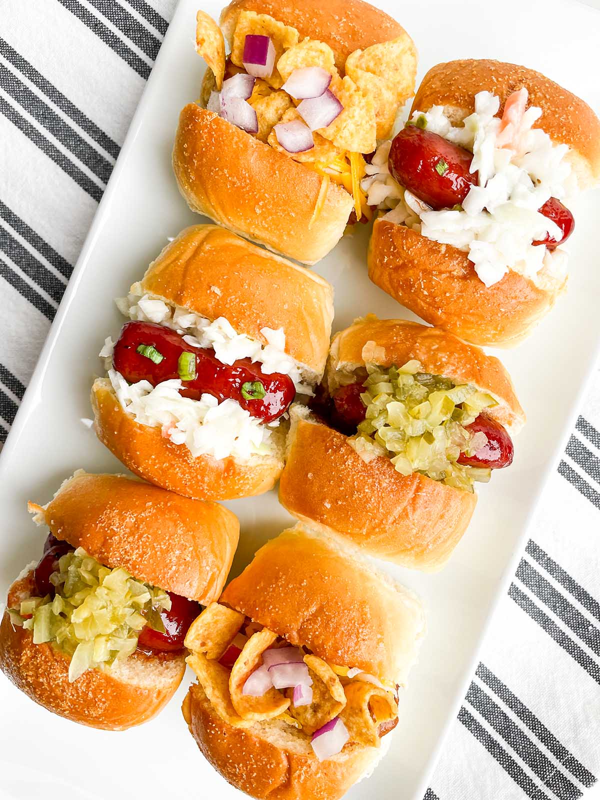mini hot dog appetizers on a white platter.